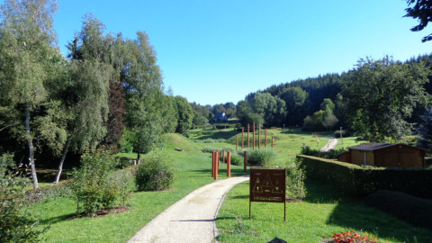 Camping Troisvierges en Clervaux, Luxemburgo con paisaje verde, árboles y un sendero en el parque.