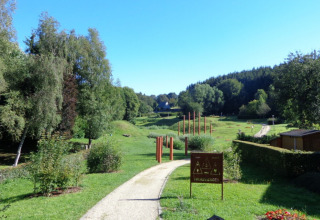 Camping Troisvierges à Clervaux, Luxembourg avec verdure, arbres, et un chemin dans le parc de vacances.