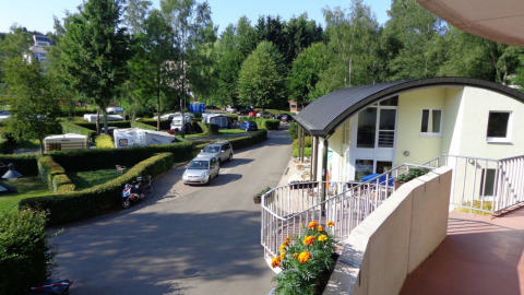 Vista de Camping Troisvierges en Luxemburgo con caravanas, setos verdes y un edificio moderno de recepción.