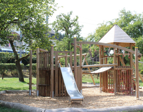 Playground with wooden climbing structure and slide at Camping Troisvierges, holiday park in Luxembourg.