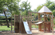 Playground with wooden climbing structure and slide at Camping Troisvierges, holiday park in Luxembourg.