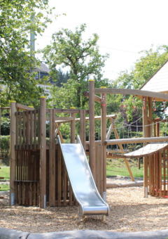 Parque infantil con estructura de madera y tobogán en Camping Troisvierges, parque vacacional en Luxemburgo.
