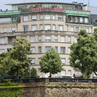 Fachada del Grand Hôtel Cravat cerca de Troisvierges, tras árboles y un muro en Clervaux, Luxemburgo.