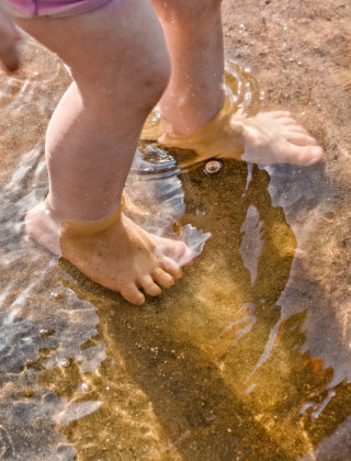 Pies descalzos de un niño jugando en aguas poco profundas cerca de Troisvierges, Luxemburgo.