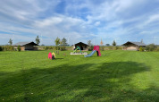Tenda safari al Boerderijcamping de Hinde nei Paesi Bassi con parco giochi e pale eoliche sullo sfondo.