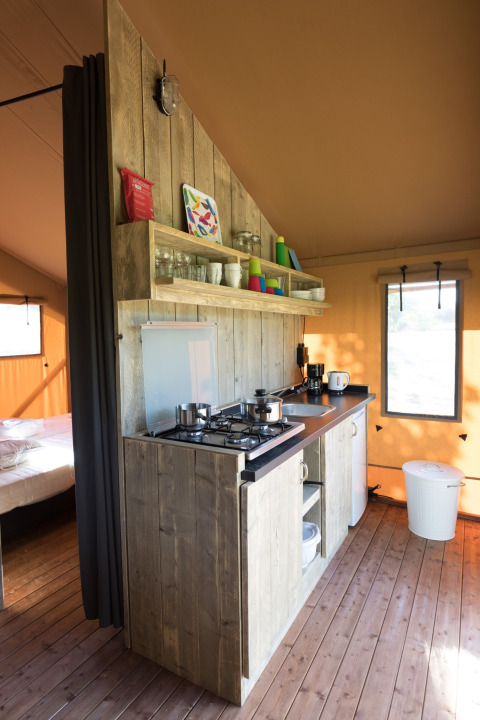 Køkkenområde i en safariteltsuite med træelementer og åbne hylder på Agriturismo Le Sorgive e Le Volpi.