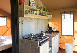 Køkkenområde i en safariteltsuite med træelementer og åbne hylder på Agriturismo Le Sorgive e Le Volpi.