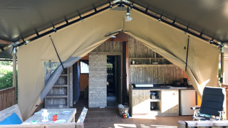 Udsigt til safari-telt med sanitære faciliteter på Camping De l'Olivigne, Frankrig. Udendørs terrasse, køkken.