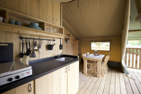 Cocina y comedor de madera en una tienda de Camping Mareveld, parque de vacaciones en Limburgo, Países Bajos.