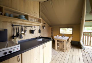 Cocina y comedor de madera en una tienda de Camping Mareveld, parque de vacaciones en Limburgo, Países Bajos.