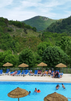 Camping l'Ardechois holiday park in Auvergne-Rhône-Alpes, France with outdoor pool and scenic mountain backdrop.