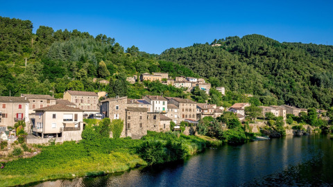 Il campeggio l'Ardechois in Auvergne-Rhône-Alpes, Francia, si trova accanto a un fiume e colline verdeggianti.