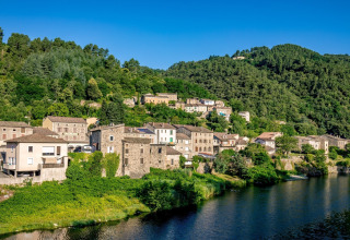 Il campeggio l'Ardechois in Auvergne-Rhône-Alpes, Francia, si trova accanto a un fiume e colline verdeggianti.