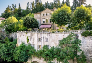 Storslået feriepark i Auvergne-Rhône-Alpes, Frankrig, omgivet af frodige træer og roligt vand.