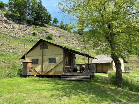 Tienda safari tipo lodge con instalaciones sanitarias en Camping l'Ardechois, Francia, rodeada de naturaleza.
