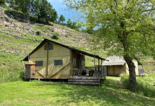 Safari-lodgetelt med sanitære faciliteter på Camping l'Ardechois i Frankrig, omgivet af natur og bakker.