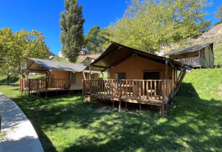 Luxe safaritenten met houten terras bij Camping l'Ardechois in Auvergne-Rhône-Alpes, Frankrijk op zonnige dag.