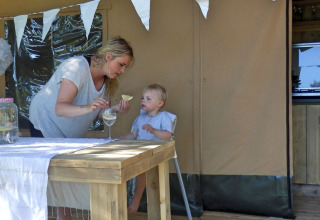 Mère et enfant profitent du glamping dans un parc de vacances, avec déco cosy et table en bois dehors.