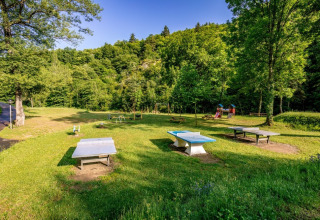 Udendørs legeplads og bordtennisborde i grønne omgivelser på Camping l'Ardechois i Auvergne-Rhône-Alpes.