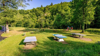 Outdoor playground and table tennis area at Camping l'Ardechois holiday park in Auvergne-Rhône-Alpes, France.