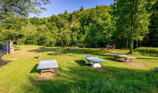 Outdoor playground and table tennis area at Camping l'Ardechois holiday park in Auvergne-Rhône-Alpes, France.