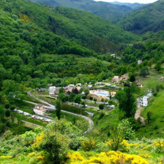 Panoramic view of Camping l'Ardechois holiday park surrounded by lush hills in Auvergne-Rhône-Alpes, France.