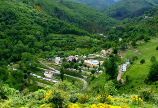 Panoramisch zicht op Camping l'Ardechois, omgeven door groene heuvels in Auvergne-Rhône-Alpes, Frankrijk.