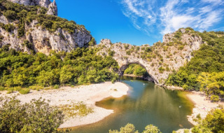 Natural stone arch over a river with lush greenery in the Gluiras area, Auvergne-Rhône-Alpes, France.