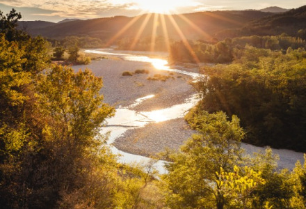 Sunset over a river and lush landscape near Gluiras in Auvergne-Rhône-Alpes, France.