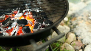 Close-up of a barbecue with hot coals at a holiday park offering glamping accommodations outdoors.