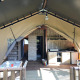 Indvendigt udsyn af et safaritelt med køkken, spisebord, trædæk og komfortabel campingindretning.