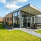 Moderne tiny house Knilles ved Tusken de Marren, Nederlandene, med glasfacader og hyggelig have.