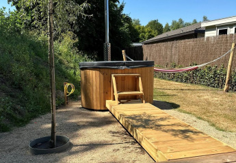 Buiten hottub en houten loopbrug bij Veranda chalet met hangmat op Camping Sevink Molen, Nederland.
