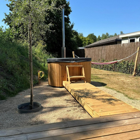 Outdoor hot tub and wooden walkway at Veranda chalet with hammock at Camping Sevink Molen, Netherlands.