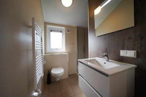 Baño moderno en Tiny kids cottage en Kaatsheuvel, Países Bajos, con lavabo, inodoro y espejo.