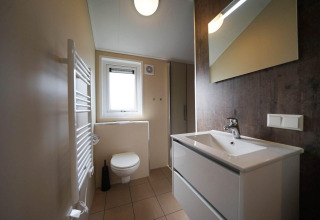 Baño moderno en Tiny kids cottage en Kaatsheuvel, Países Bajos, con lavabo, inodoro y espejo.