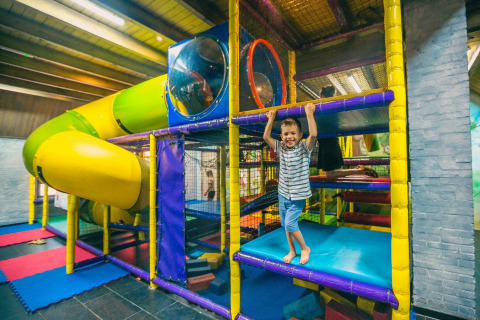 Niño jugando en un colorido parque infantil interior con tobogán en Tiny kids cottage en Kaatsheuvel, Países Bajos.