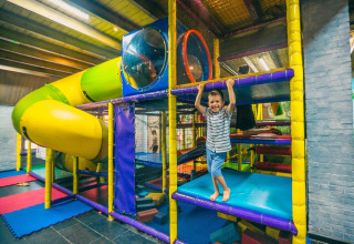 Niño jugando en un colorido parque infantil interior con tobogán en Tiny kids cottage en Kaatsheuvel, Países Bajos.