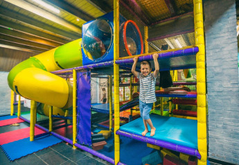 Niño jugando en un colorido parque infantil interior con tobogán en Tiny kids cottage en Kaatsheuvel, Países Bajos.