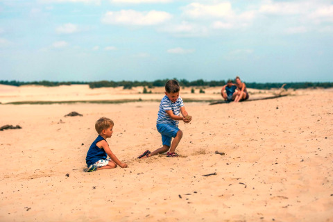 Twee kinderen spelen in het zand bij Tiny House in Kaatsheuvel, Nederland, ouders zitten op de achtergrond.
