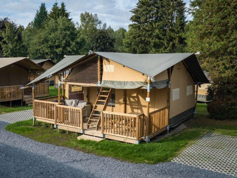 Glamping tent with wooden porch at Arden Parks Signy l'Abbaye, a green holiday park in Grand Est, France.