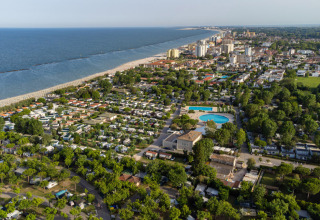 Luftfoto af Vigna sul Mar Family Camping Village ved stranden i Emilia-Romagna, Italien, omgivet af træer.