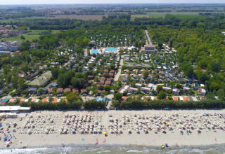 Vista aérea de Vigna sul Mar Family Camping Village con playa llena y sombrillas en Emilia-Romaña, Italia.