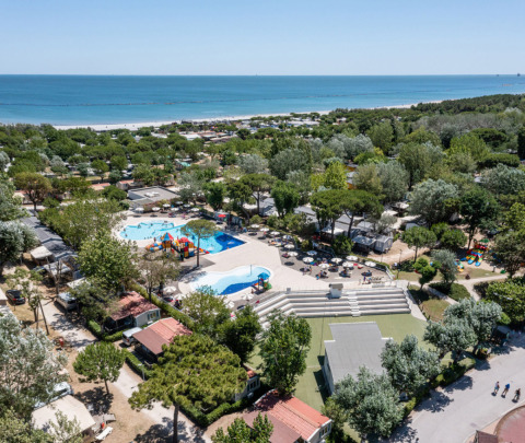 Vista aérea de Vigna sul Mar Family Camping Village en Emilia-Romagna, Italia, con piscina, árboles y playa.