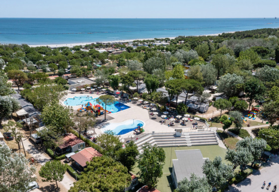 Vista aérea de Vigna sul Mar Family Camping Village en Emilia-Romagna, Italia, con piscina, árboles y playa.