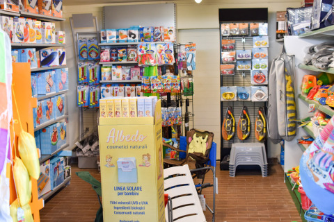 Tienda de juguetes y artículos de playa con protectores solares y equipo de snorkel en un camping en Italia.