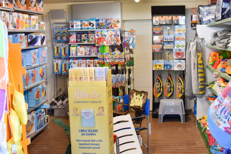 Winkel met speelgoed en strandartikelen zoals zonnebrandcrème en snorkelsets in een vakantiepark in Italië.