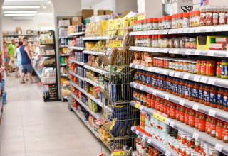 Rayon d’un supermarché à Vigna sul Mar Family Camping Village, Italie, avec des clients et des produits.