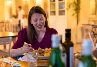 Woman enjoys dinner at a restaurant in Vigna sul Mar Family Camping Village, Emilia-Romagna, Italy.