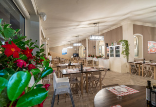 Indbydende restaurantområde på Vigna sul Mar Family Camping Village i Emilia-Romagna, Italien, med træmøbler.